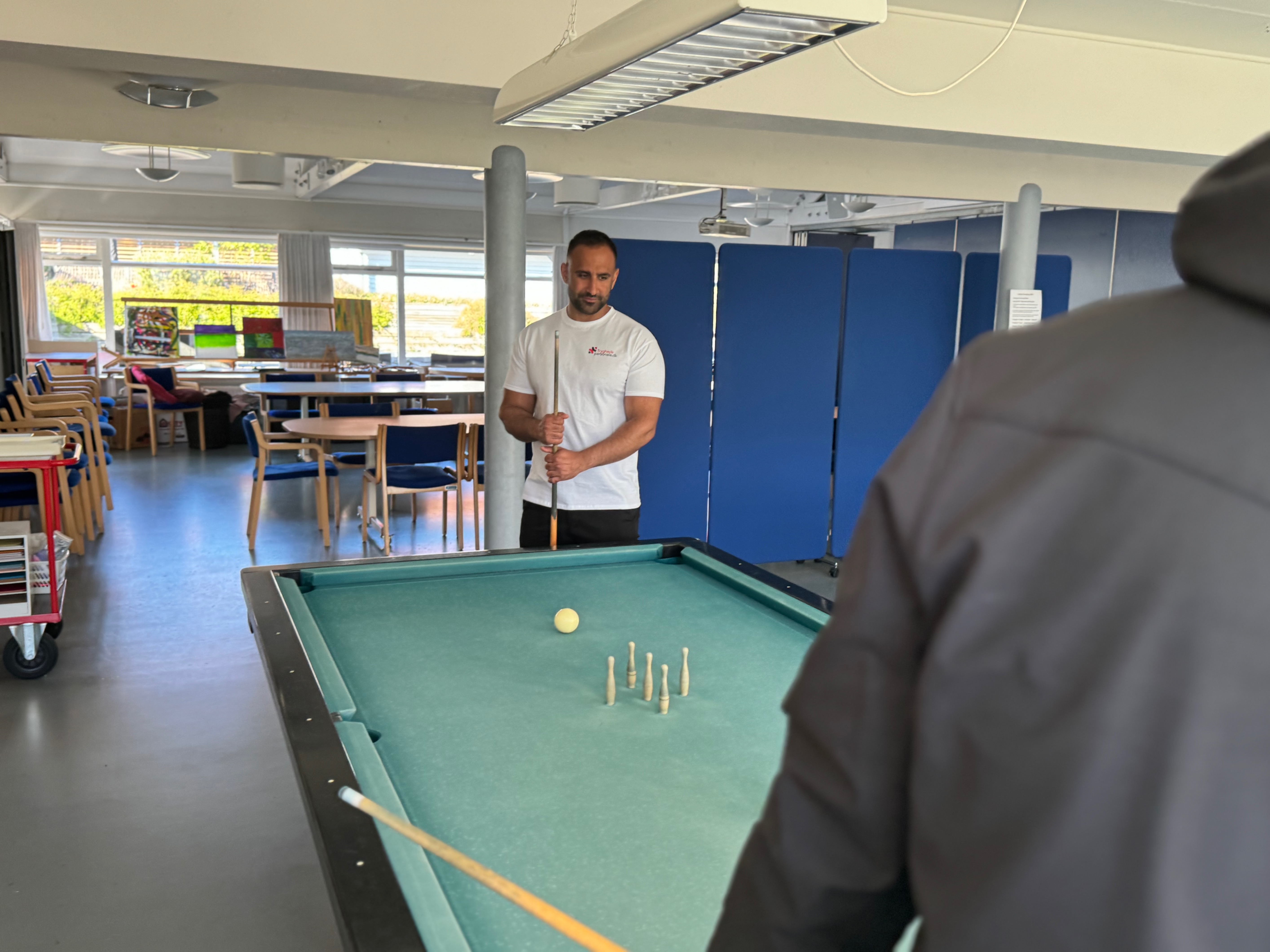 Tryghedspersonale spiller billard med borger i fællesstuen